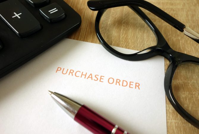 Purchase order, pen, calculator and glasses on desk